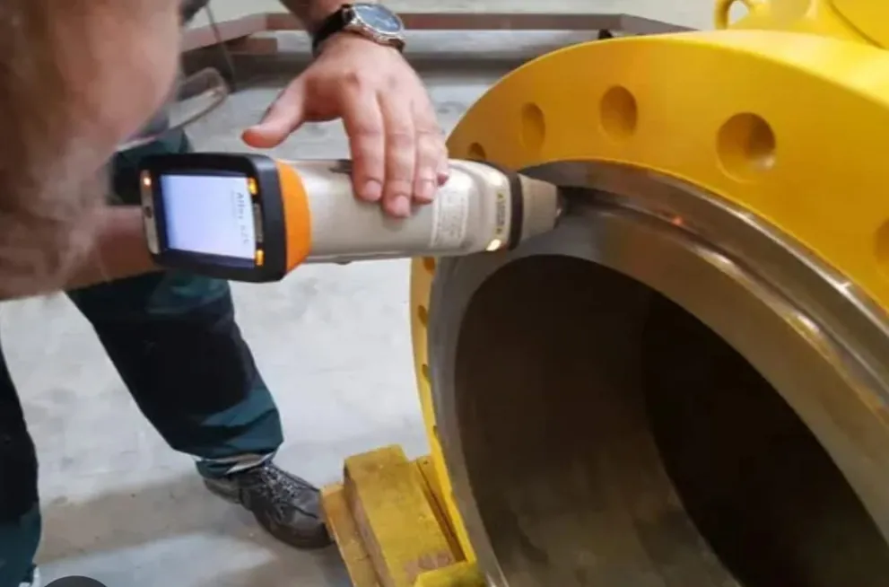 Handheld analyser inspecting a flanged pipe component